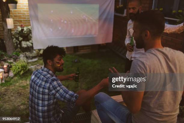friends watching soccer game on big screen in backyard - projection equipment stock pictures, royalty-free photos & images