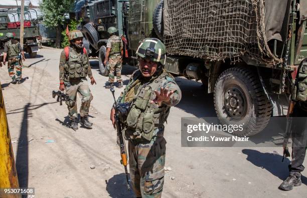 An Indian army officer with a camera fitted helmet stops journalists near the gun battle site, during a gun battle between Indian armed forces and...