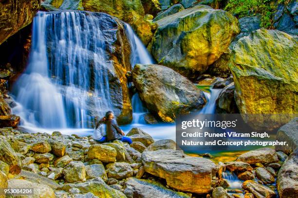 a young couple sitting at a waterfall - gangtok ストックフォトと画像