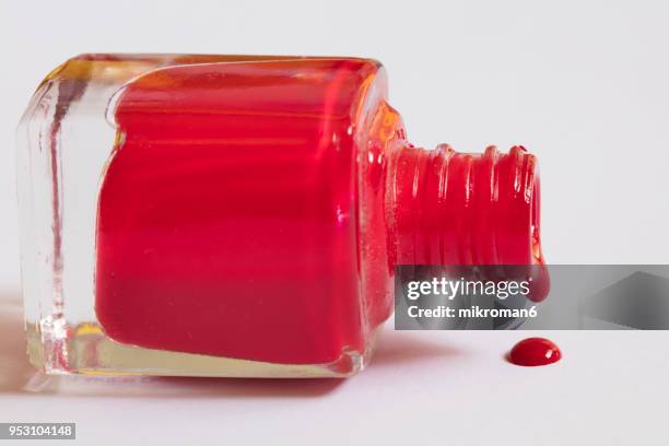 red nail varnish spilling onto white background. - rode nagellak stockfoto's en -beelden