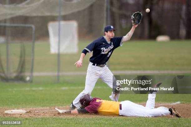 Thornton Academy senior Brady Lambert slides safely into third base as Portland's William Synder reaches up to catch the ball during their game in...