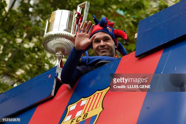 Barcelona's Spanish midfielder Andres Iniesta waves from an open-top bus as the team parades to celebrate their 25th La Liga title in Barcelona on...