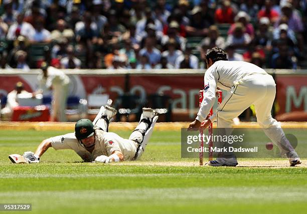 Saeed Ajmal of Pakistan misses the return throw as Shane Watson of Australia dives to make his ground during day one of the First Test match between...
