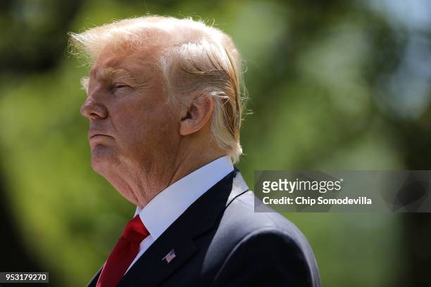 President Donald Trump listens to reporters' questions during a joint news conference with Nigerian President Muhammadu Buhari in the Rose Garden of...