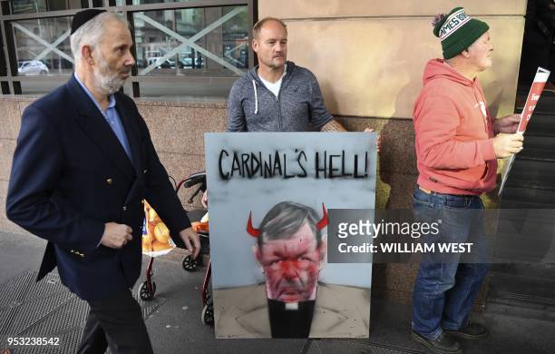 Protesters hold up placards as Vatican finance chief Cardinal George Pell arrives in court under a heavy police presence in Melbourne on May 1, 2018....