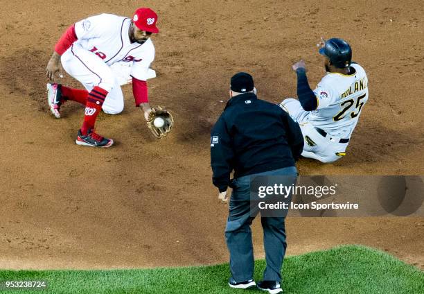 Umpire Eric Cooper watches as Washington Nationals left fielder Howie Kendrick scoops up the ball while Pittsburgh Pirates right fielder Gregory...