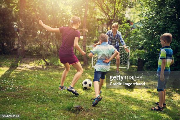 familie plezier te voetballen in de tuin - familie sport stockfoto's en -beelden