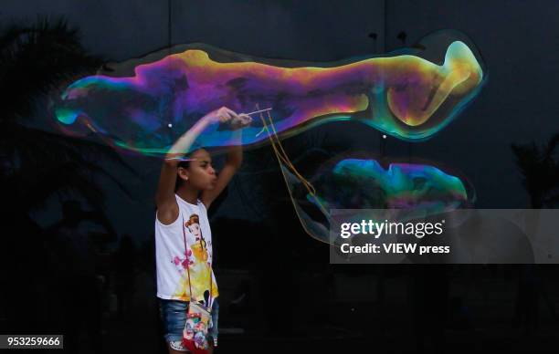 Girl play as she make giant soap bubbles in the City Park Dom Nivaldo Monte, on April 29, 2018 in Natal.