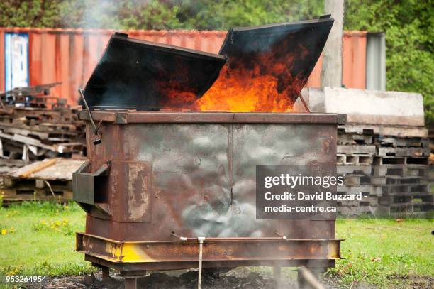 a burning dumpster fire, as part of a fire fighter's training exercise. squamish bc, canada. april 29, 2018. - afvalcontainer stockfoto's en -beelden