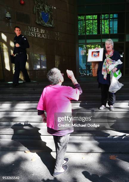 Supporter for Cardinal George Pell holds up paintings in front of a protestor at Melbourne Magistrates' Court on May 1, 2018 in Melbourne, Australia....