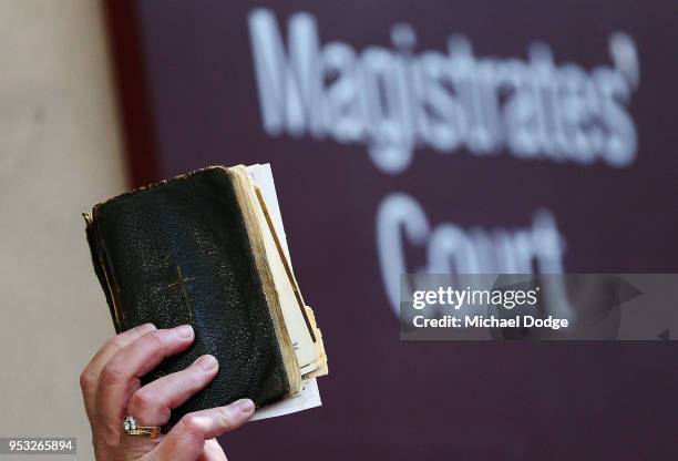 Supporter for Cardinal George Pell holds up the Bible before he was committed to stand trial at Melbourne Magistrates' Court on May 1, 2018 in...