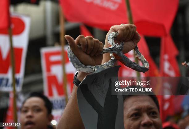 Activists along with workers break a mock chain during the May Day rally near Malacanang Palace in Manila on May 1, 2018.