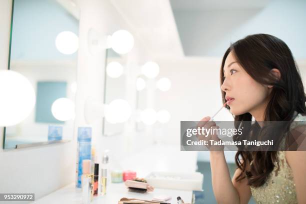 woman is putting on make up at backstage dressing room. - woman backstage stock pictures, royalty-free photos & images