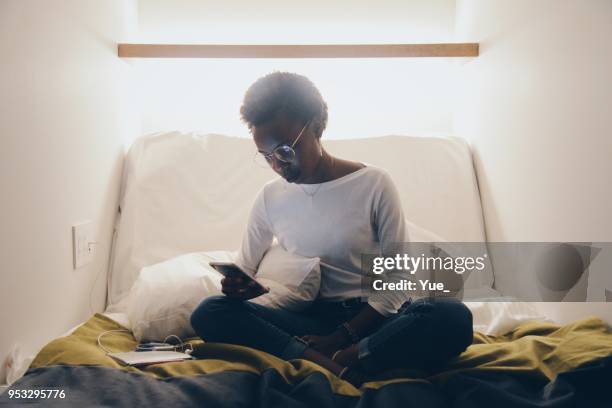 young woman watching smart phone on bed of capsule hotel - hostel stock pictures, royalty-free photos & images