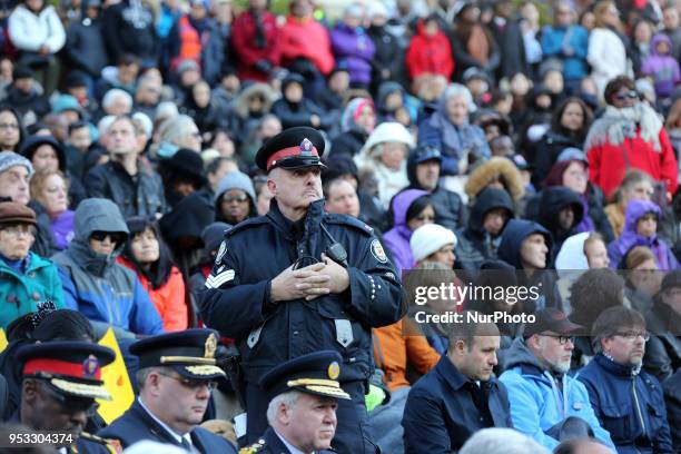 Police sergeant stands guard as thousands of people attended an inter-faith vigil at Nathan Phillips Square in memory of the 10 people killed and 15...