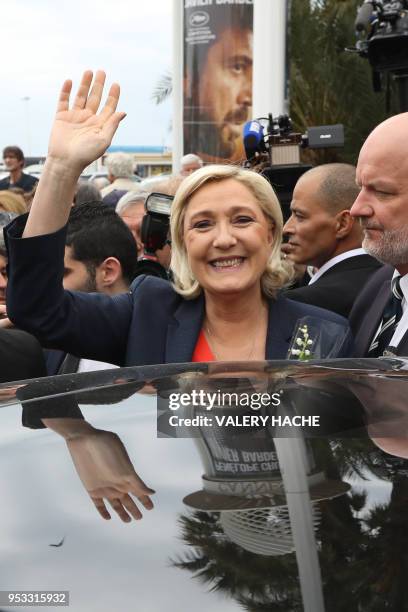 President of the French far-right Front National party Marine Le Pen waves as she gets into a car after placing a spray of flowers under the statue...