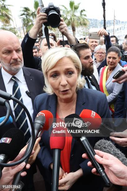 President of the French far-right Front National party Marine Le Pen speaks to the press after placing a spray of flowers under the statue of "Joan...