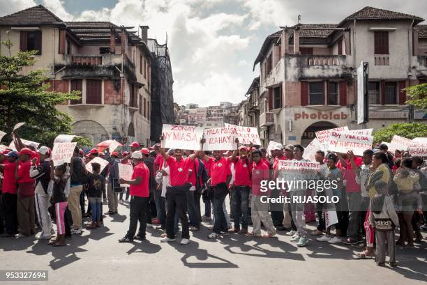 Protesters hold banners reading messages for the re-opening of the TIKO factories owned by former President Marc Ravalomanana as they take part in...