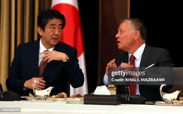 Japan's Prime Minister Shinzo Abe talks with Jordanian King Abdullah II over lunch at the Royal Palace in Amman on May 1, 2018.