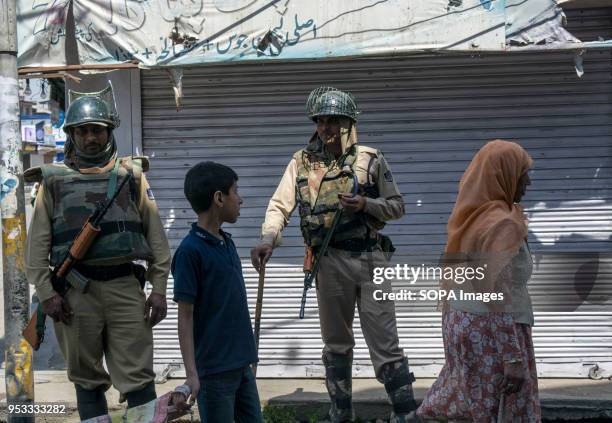 Woman with her son walks past as Indian paramilitary troops stands alert during restrictions in Downtown area of Srinagar city, summer capital of...