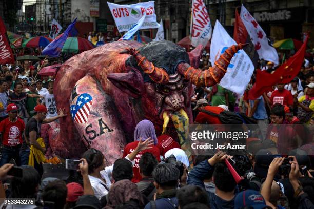 Workers and activists gather around a mock image of President Duterte as they mark Labor Day on May 1, 2018 in Manila, Philippines. Thousands of...