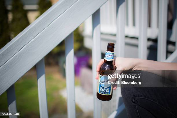 Person holds a bottle of Molson Coors Brewing Co. Blue Moon brand beer in an arranged photograph in Madison, Connecticut, U.S., on Saturday, April...