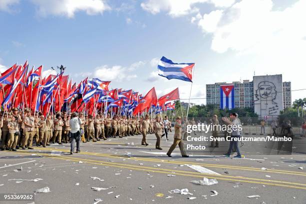 Cuban military personnel carry Cuban flags as they pass in front of the image of Che Guevara at the Ministry of Interior building as closing the...