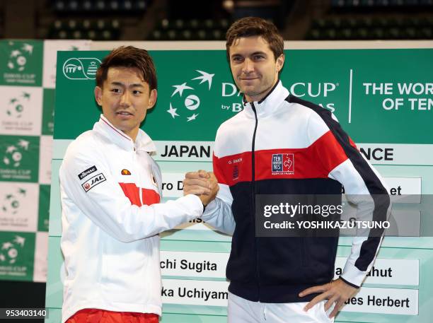 Japan's Yoshihito Nishioka shakes hands with Gilles Simon of France as they attend a drawing event of the Davis Cup World Group first round tennis...