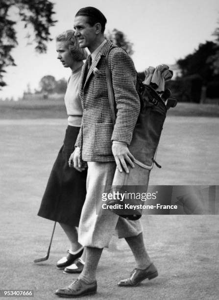Georges Carpentier sur le terrain de golf porte le sac de golf de sa fille Jacqueline, à Stoke Poges, Royaume-Uni le 7 septembre 1938.