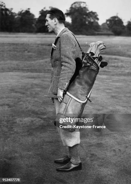 Georges Carpentier sur le terrain de golf porte le sac de golf de sa fille Jacqueline, à Stoke Poges, Royaume-Uni le 7 septembre 1938.