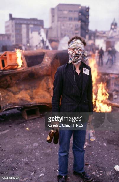 Emeutier devant une voiture incendiée en 1981 à Belfast en Irlande du Nord.