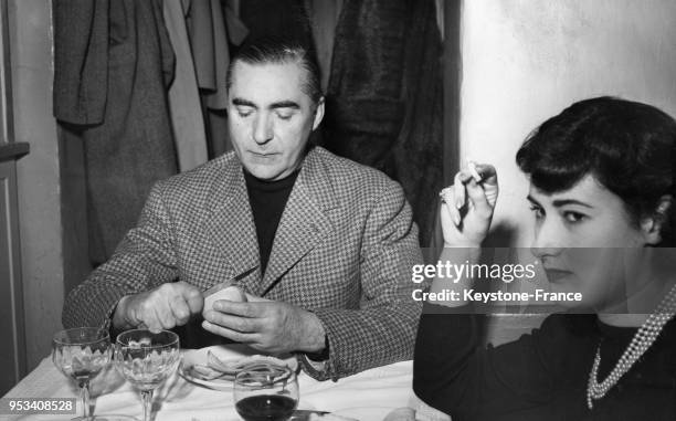 écrivain italien Curzio Malaparte épluchant une pomme, son fruit préféré, dans un restaurant, à droite l'actrice italienne Bianca Maria Agnesi, à...