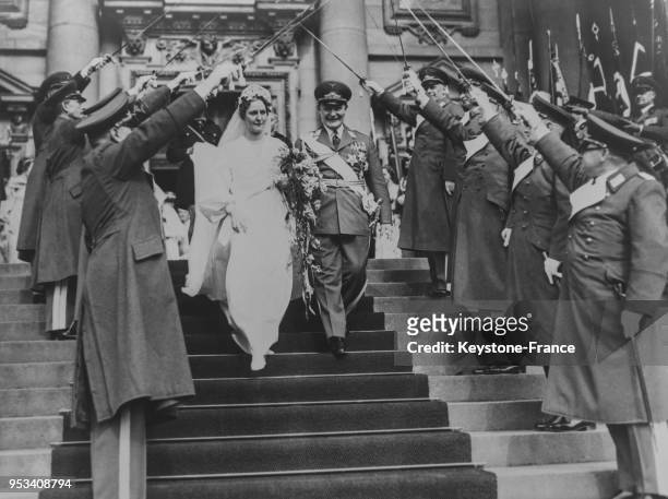 Après la cérémonie religieuse, les mariés passent sous la voûte d'acier formée par les épées des officiers aviateurs, à Berlin, Allemagne le 11 avril...