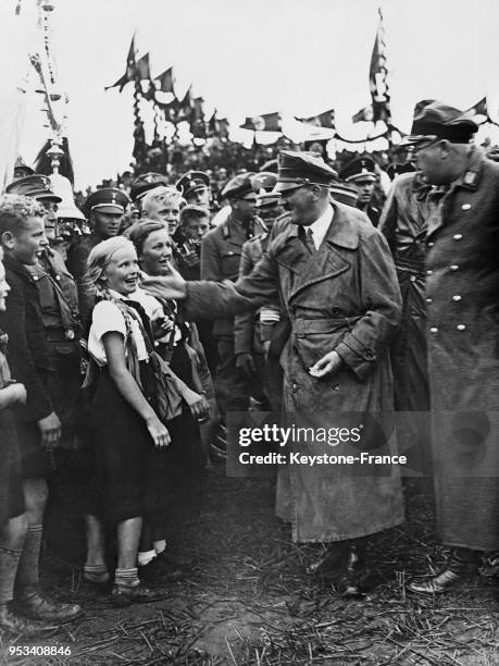 Hitler caresse la joue d'une petite fille lors d'un passage en revue des Jeunesses Hitlériennes, circa 1930 à Berlin, Allemagne.