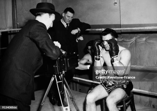 Le boxeur français Robert Villemain posant pour un photographe de presse avec ses gants sous l'oeil de son entraîneur Jean Bretonnel le 2 janvier...