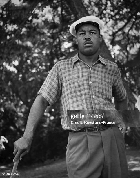Le boxeur Joe Louis joue au golf sous la chaleur sur le green de l'Engineers Country Club à Log Island, New York, aux Etats-Unis circa 1940.