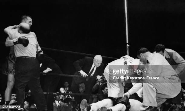 Les soigneurs raniment le boxeur Rocky Graziano vaincu par KO, pendant que l'arbitre tire sur son short et que le vainqueur Tony Zale est félicité au...