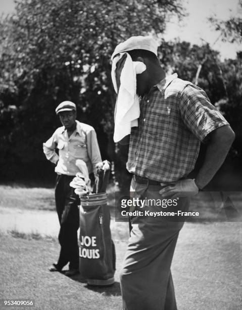 Le boxeur Joe Louis joue au golf sous la chaleur sur le green de l'Engineers Country Club à Long Island, New York, aux Etats-Unis circa 1940.