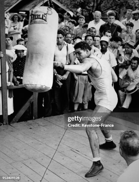 Joe Louis boxant sur le sac de frappe pendant son entraînement public, à Pompton Lakes, New Jersey, Etats-Unis en août 1937.