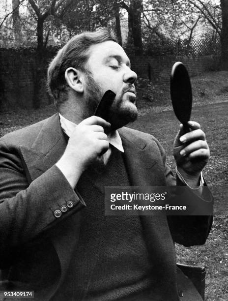 Acteur britannique Charles Laughton se peigne la barbe, à Londres, Royaume-Uni en 1936.
