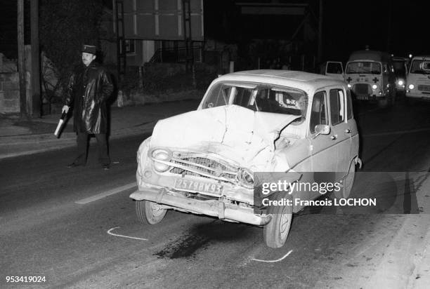 Un policier régle la circulation à côté d'une Renault 4 endommagée lors d'un accident sur la voie publique en janvier 1975 à Paris, France.