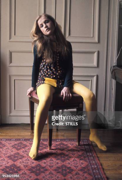 Portrait de la comédienne Isabelle Huppert portant des collants jaunes assises sur un tabouret, circa 1970.