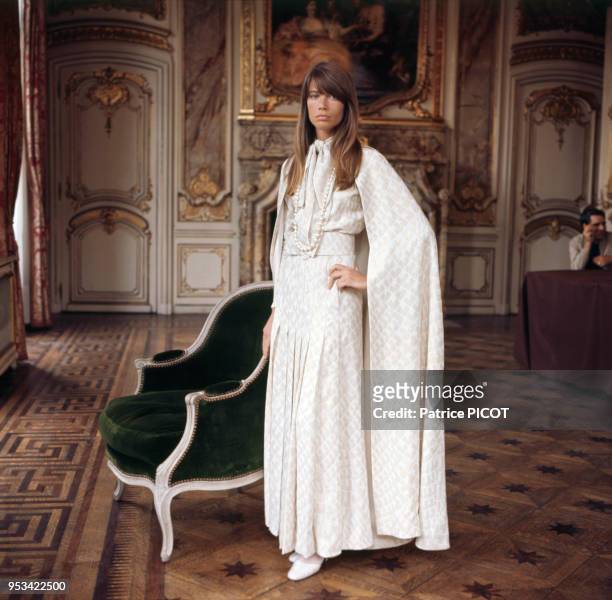 Portrait de la chanteuse Françoise Hardy en robe longue dans une salle de château, circa 1970.
