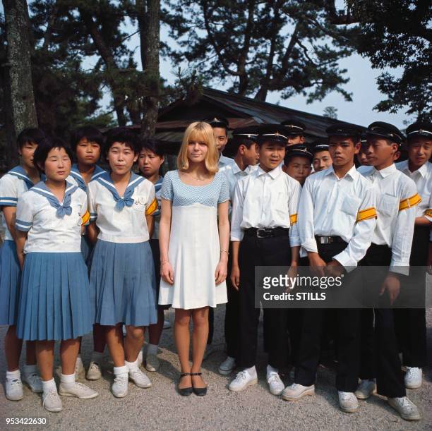 Portrait de la chanteuse France Gall entourée de choristes asiatiques en uniforme circa 1960.
