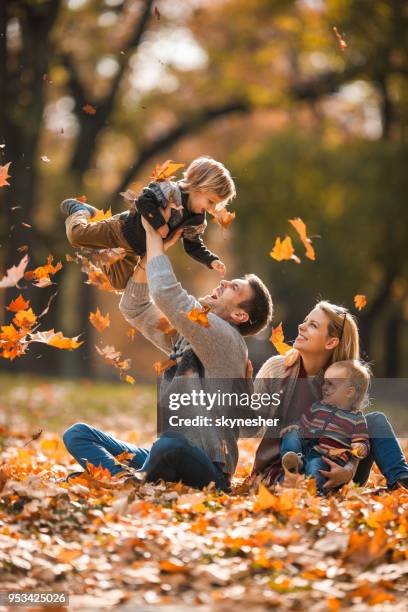 gelukkige ouders plezier met hun kleine kinderen in herfstdag. - young leafs stockfoto's en -beelden