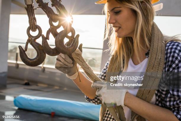 vrouwelijke bouwvakker werken met kabel lier op een terras. - jonglieren stockfoto's en -beelden