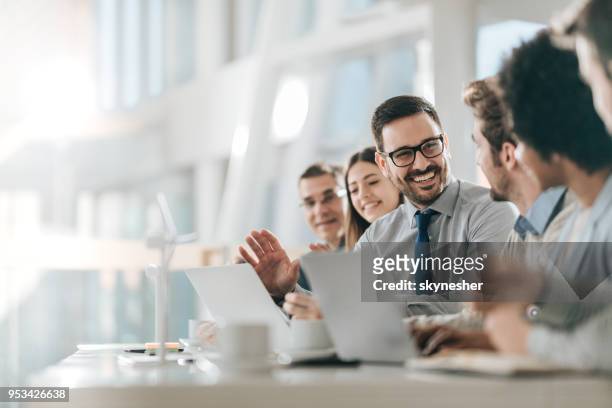 hombre de negocios feliz hablando con sus colegas en una reunión en la oficina, - personas reunidas fotografías e imágenes de stock