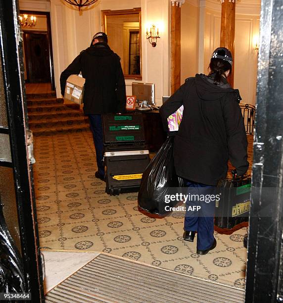 Police officers carry equipment as they enter on December 26, 2009 the building in central London where a student who is alleged to have attempted to...