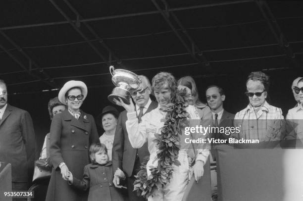 Austrian racing driver Jochen Rindt wins 1970 Monaco Grand Prix and holds his trophy in the presence of Rainier III, Prince of Monaco and Princess of...