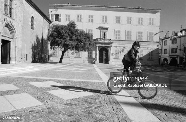 Jeune garçon faisant du vélo sur la place de la mairie avec à gauche la cathédrale Saint-Léonce en décembre 1988 à Fréjus, Var.